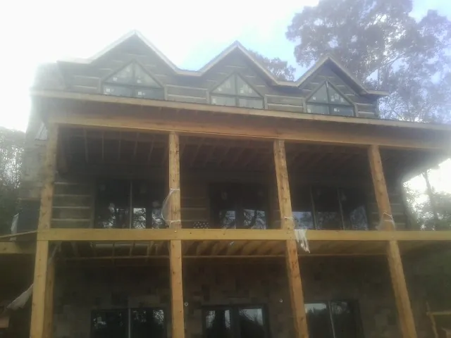 Dormers and porch framing on a large log home under construction — Roof Coating work by our crew in Ypsilanti