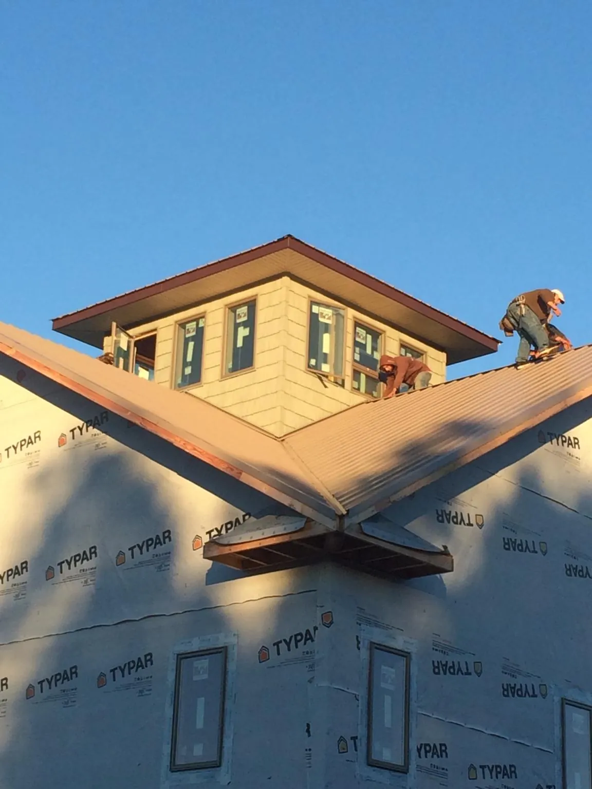 Roofers working around a rooftop cupola on a new metal roof at sunset — Roof Waterproofing in Ypsilanti by Roofing Brothers
